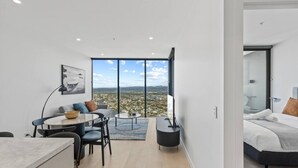 Una sala moderna con comedor, un ventanal con vista a la ciudad y un dormitorio independiente.