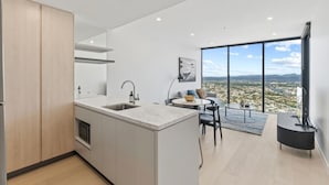 Una cocina moderna con una isla grande, un área de comedor con vistas y un espacio de sala con televisor.
