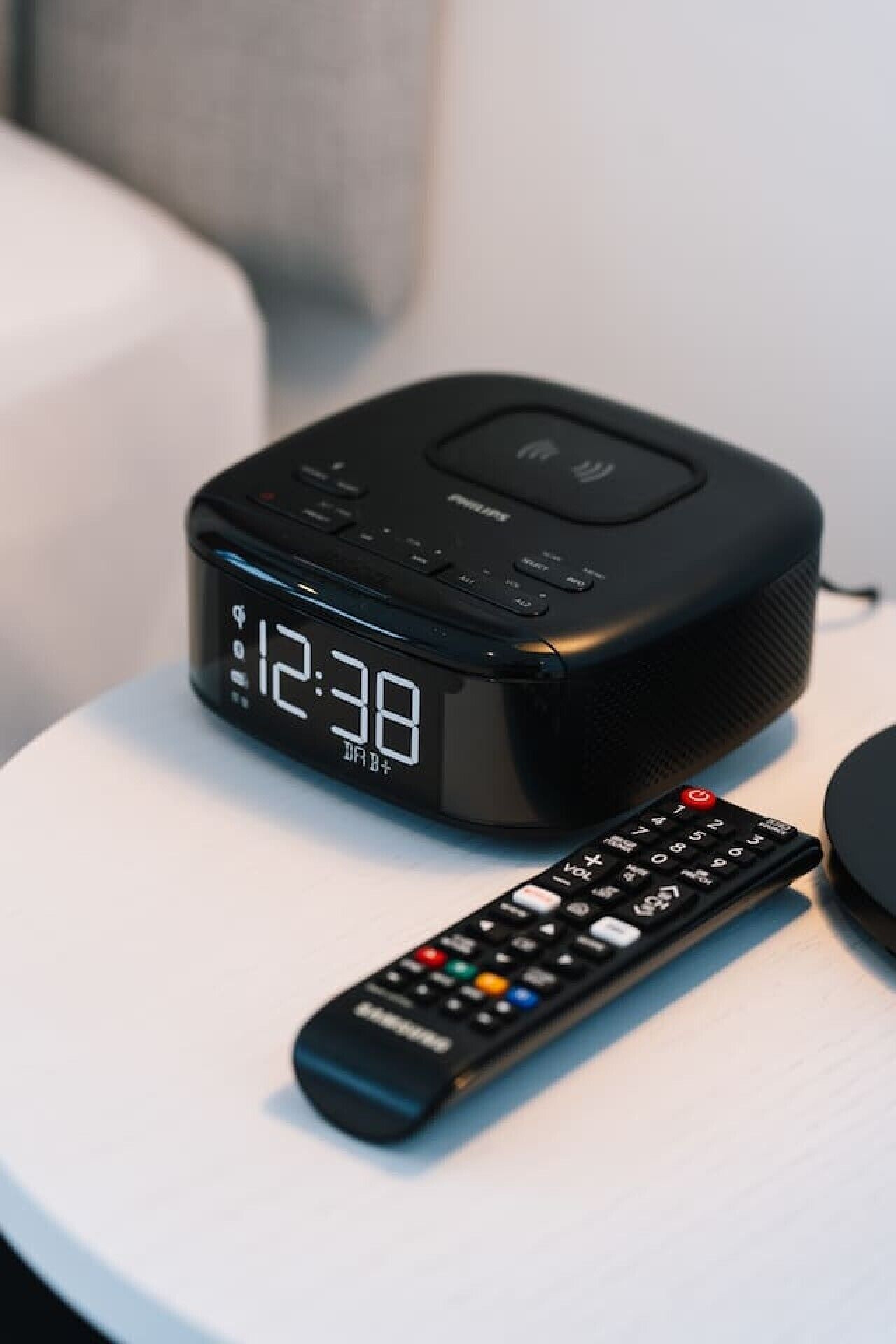 Un haut-parleur Philips noir et une télécommande sur une surface blanche.