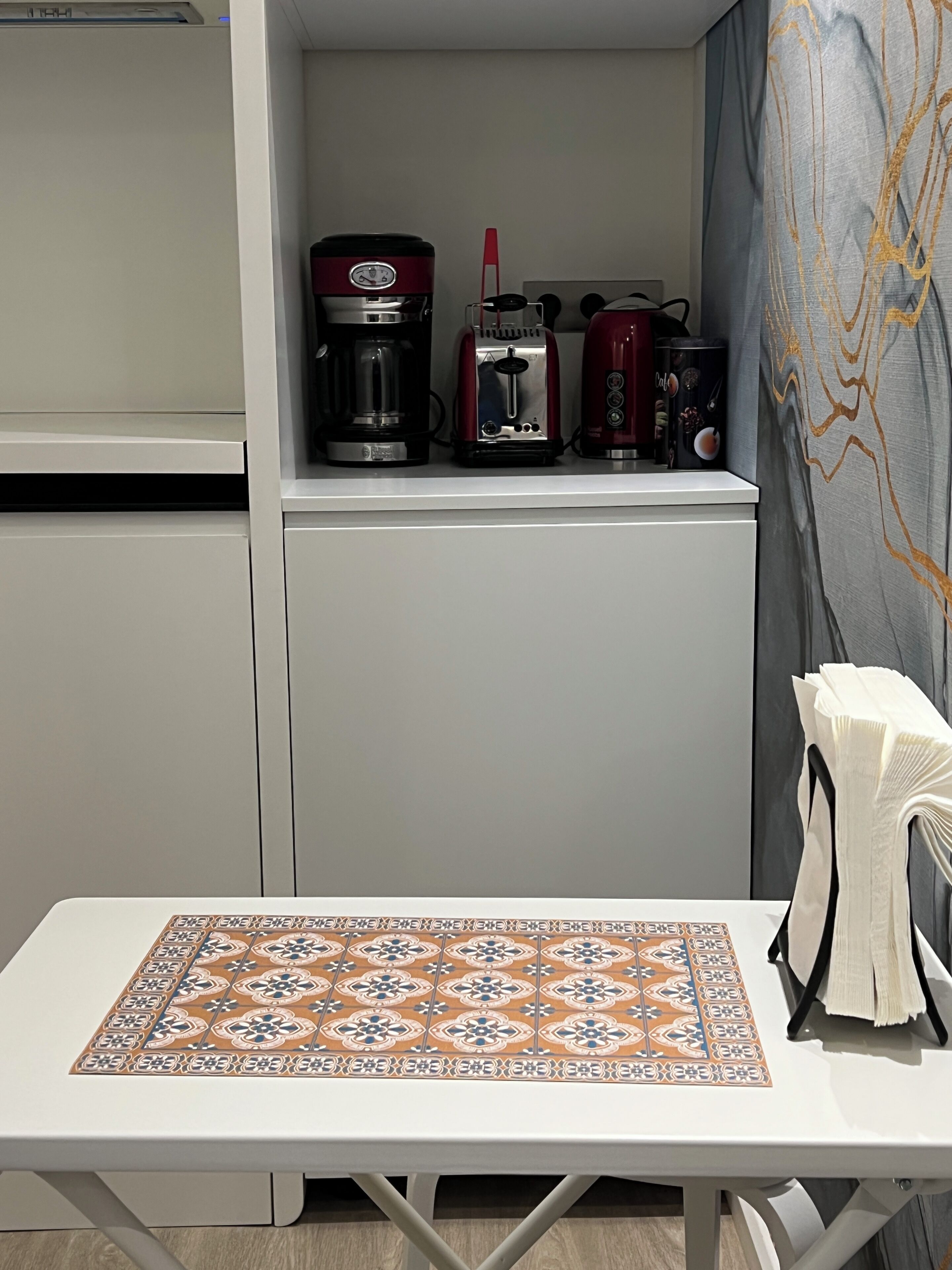 A small kitchenette with a coffee maker, toaster, and a microwave on the countertop.
