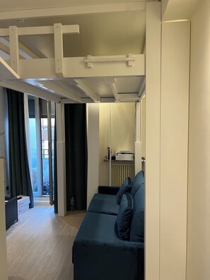 Ein modernes Wohnzimmer mit einer Couch, einer Heizung und einer Tür, die auf einen Balkon führt.