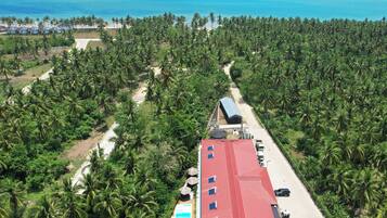 A resort with a red-roofed building, a swimming pool, and a view of the ocean.