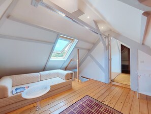 A modern loft bedroom with a sloped ceiling, skylight, wooden flooring, and a white sofa. - Ty Yannick by Interhome (Ploumanach)