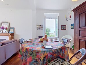 A dining area with a round table covered by a colorful tablecloth, surrounded by chairs. - Ty Yannick by Interhome (Ploumanach)