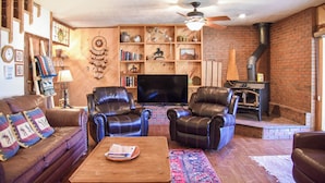 A cozy living room with leather sofas, a flat-screen TV, a fireplace, and a brick wall. - Dream Catcher

Dream Catcher (Red River)