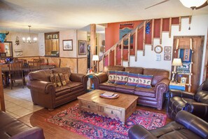 Ein gemütliches Wohnzimmer mit Ledersofas, einem Couchtisch und einem gemusterten Teppich.