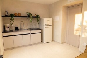 A compact kitchen with a sink, countertop, and a white refrigerator. - Luxe Apartment w/ Panoramic View & Terrace in Heart of Naples (Napoli)