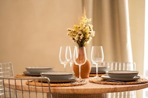 A dining table set with plates, glasses, and a vase with flowers. - Luxe Apartment w/ Panoramic View & Terrace in Heart of Naples (Napoli)