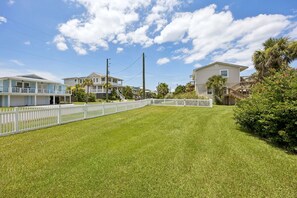 A residential area with a well-maintained lawn, white picket fence, and houses with balconies.