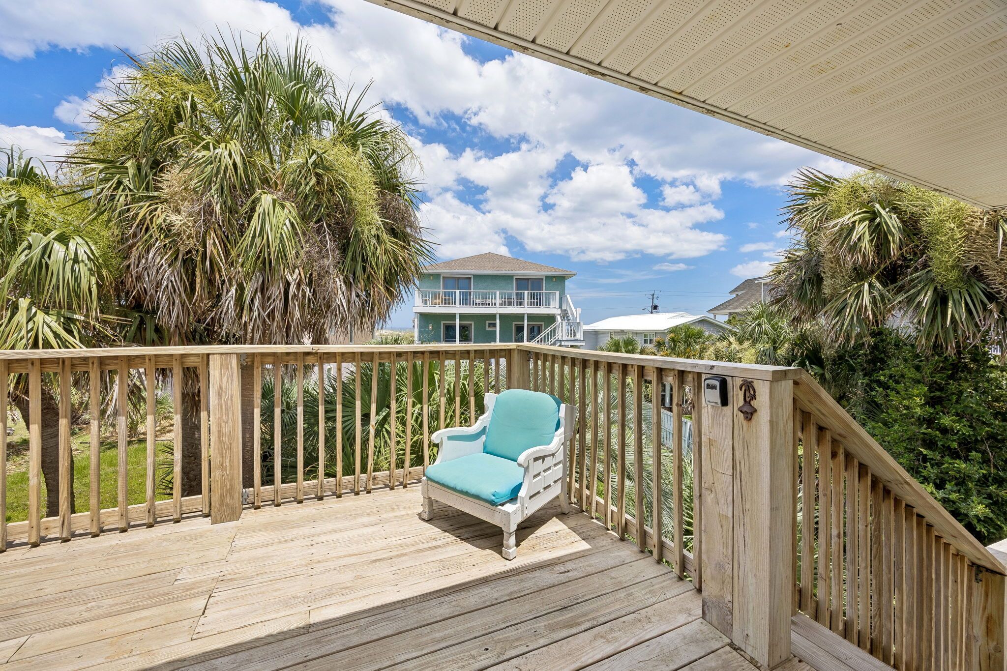 A wooden deck with a single white chair and a wooden railing.