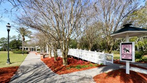 A pathway lined with trees and a white fence, leading to a gazebo. A sign indicates the location is Coastal Georgia, Greenway, St. Mary's Trail. - Downtown St. Marys Retreat | Sleeps 5 (St. Marys)