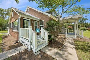 A two-story brick house with a front porch, a covered porch area, and a small garden. - Downtown St. Marys Retreat | Sleeps 5 (St. Marys)
