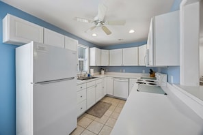 A kitchen with white cabinets, a refrigerator, a stove, and a ceiling fan. - Downtown St. Marys Retreat | Sleeps 5 (St. Marys)
