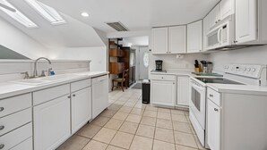 A modern kitchen with white cabinets, a sink, a microwave, and a stove. - Downtown St. Marys Retreat | Sleeps 2 (St. Marys)
