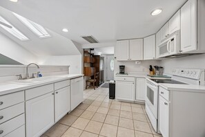 A modern kitchen with white cabinets, a sink, a microwave, and a stove. - Downtown St. Marys Retreat | Sleeps 2 (St. Marys)
