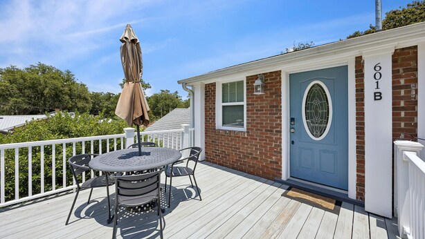 A deck with a table and chairs, a blue door with the number 601B, and a white fence. - Downtown St. Marys Retreat | Sleeps 2 (St. Marys)