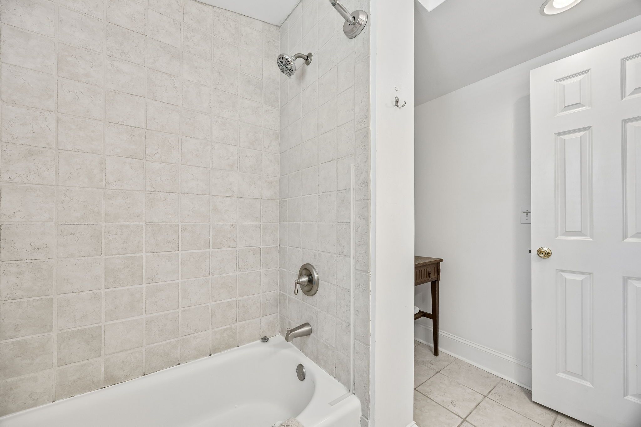 A bathroom with a bathtub, shower, and white tiled walls.