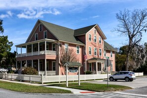 A two-story historic Spencer House Inn with a porch, a signboard, and a white picket fence. - Downtown St. Marys Retreat | Sleeps 2 (St. Marys)