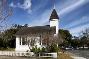 Eine kleine weiße Kirche mit einem Kirchturm, umgeben von Bäumen und einem weißen Zaun.