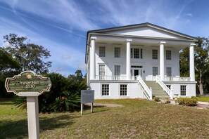 A white colonial-style building with a central staircase, large windows, and a sign indicating it is Orange Hall, established in 1830. - Downtown St. Marys Retreat | Sleeps 2 (St. Marys)