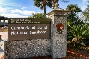 Cartell del Parc Nacional de Cumberland Island, part de la National Park Service, amb una base de pedra i un element decoratiu.