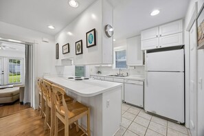 A modern kitchen with white cabinetry, a central island with stools, a built-in oven, and a refrigerator. - Downtown St. Marys Retreat | Sleeps 2 (St. Marys)