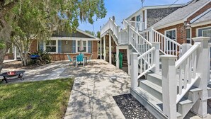 Um imóvel residencial com varanda coberta, área de estar externa e escada para um deck.