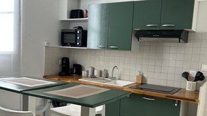 Una cocina compacta con microondas, lavamanos y armarios verdes.