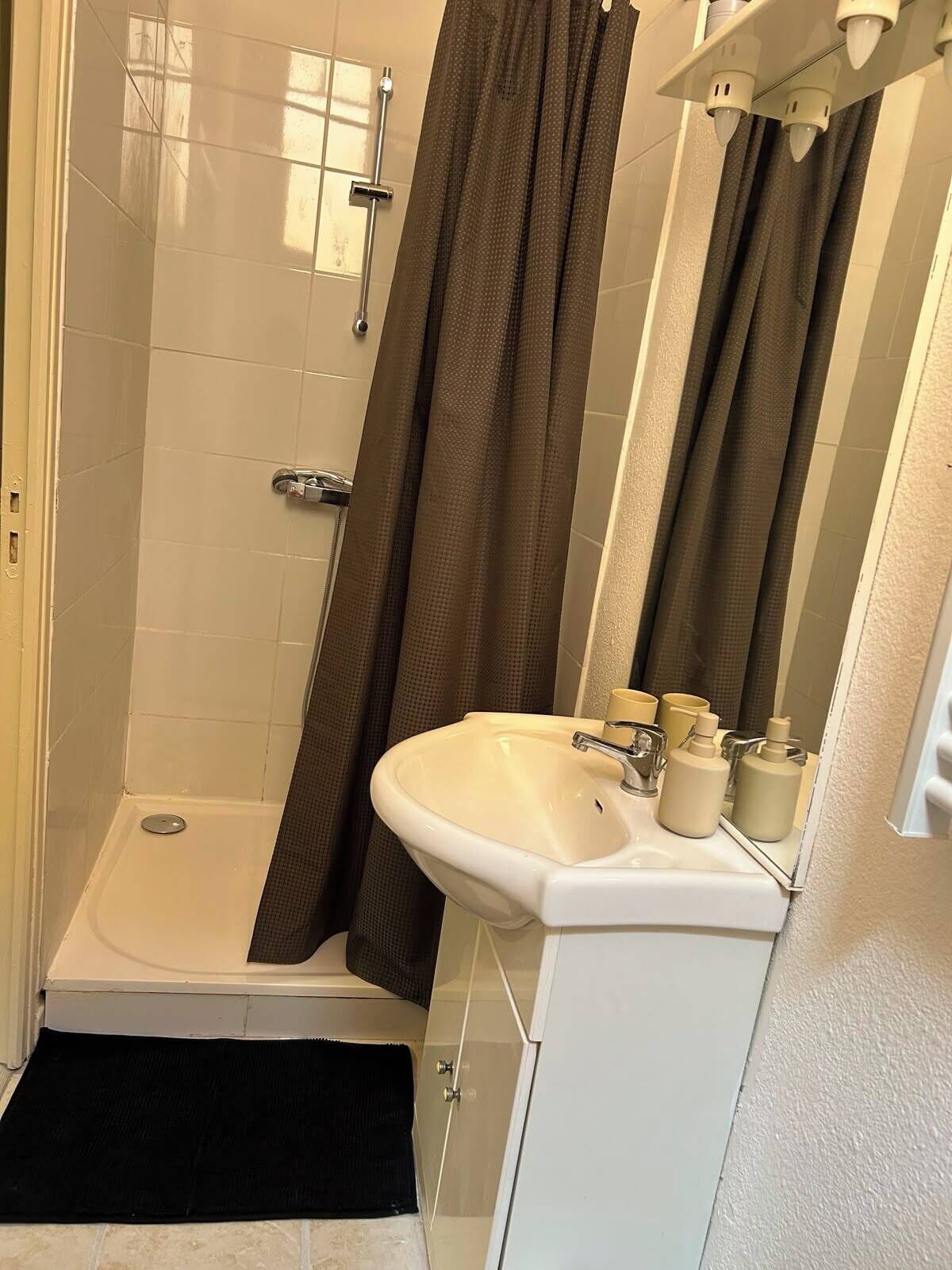 Ein Badezimmer mit Dusche, Waschbecken und Spiegel.