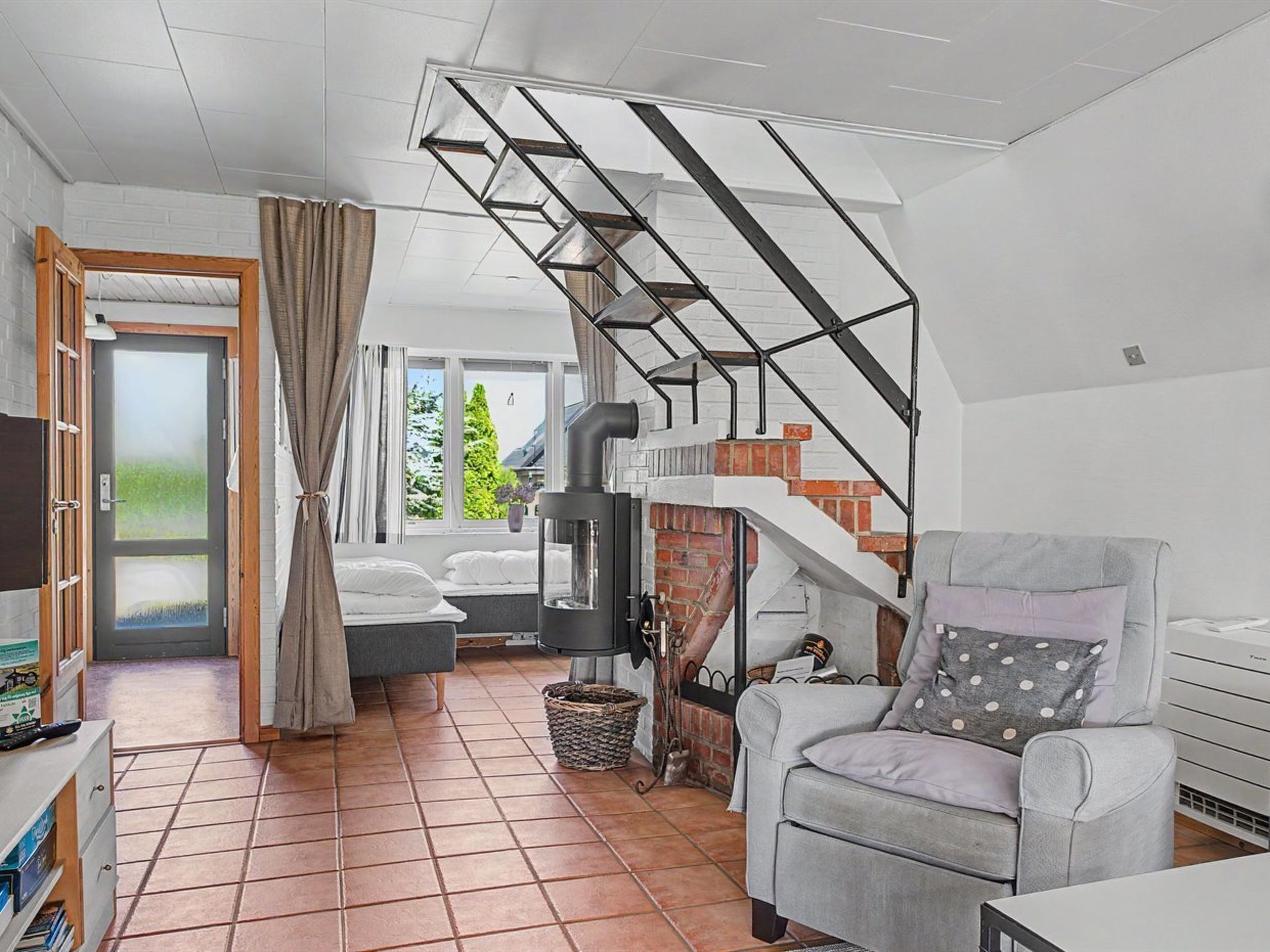 A modern living room with a sofa, a chair, a fireplace, and a staircase.