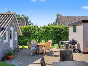 A patio with a table and chairs, a barbecue grill, and a hedge in the background. - "Rosalie" - 150m from the sea by Interhome (Otterup)