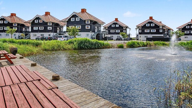 En række traditionelle huse med en træbrygge og en sø med et springvand.