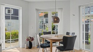 Et moderne spiseområde med et træbord, sorte stole og en hængende lampe.