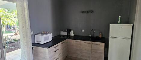 A compact kitchen with a microwave, sink, and refrigerator.
