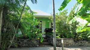 Un jardí tropical amb una escala de fusta que condueix a un edifici amb teulada verda.