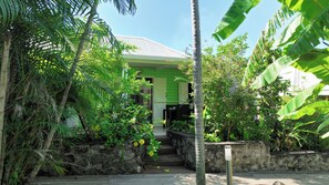 A tropical garden with a wooden staircase leading to a building with a green roof. - Ti Kaz Village Bungalow No. 3 (Saint-Louis)