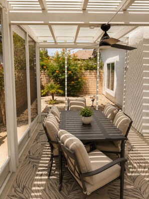 A covered patio with a table and chairs, a ceiling fan, and a view of a garden. - Modern Palm Springs Oasis - Heated Pool, Spa & Mountain View’s - Permit # 053440 (Palm Springs)