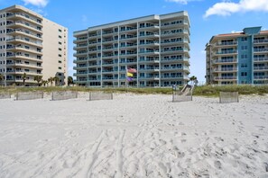 A beachfront hotel with multiple balconies, a sandy beach in the foreground, and a clear sky. - Silver Beach 801 | Beachfront & Dog-Friendly | Top Floor Corner Condo (Orange Beach)