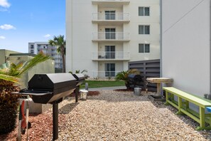 A patio area with a grill, a small table, and a bench. - Silver Beach 801 | Beachfront & Dog-Friendly | Top Floor Corner Condo (Orange Beach)