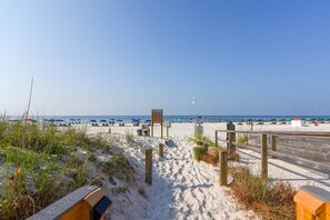 A sandy beach path leading to the ocean with beach umbrellas and a wooden boardwalk. - The Enclave 801 | Gulf Front Corner Condo | Wraparound Balcony | My Beach Getaways (Orange Beach)