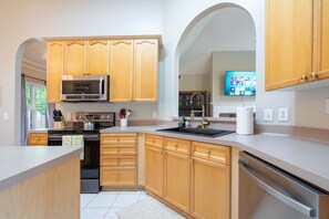 A modern kitchen with wooden cabinets, stainless steel appliances, and a built-in oven. - LakePoint 4BR Retreat with Game Room (Cartersville)