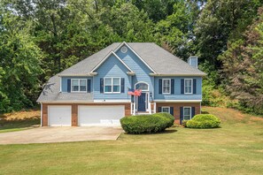 A two-story house with a garage, a front porch, and a well-maintained lawn. - LakePoint 4BR Retreat with Game Room (Cartersville)