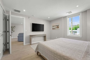 Une chambre à coucher avec un lit, un bureau, une télévision et une fenêtre donnant sur un beau paysage.