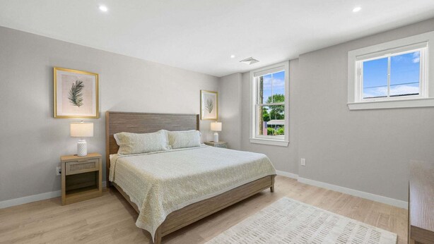 Een slaapkamer met een bed, nachtkastjes, een raam en uitzicht op groen.