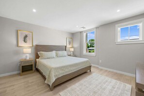 Ein Schlafzimmer mit einem Bett, Nachttischen, einem Fenster und Blick ins Grüne.
