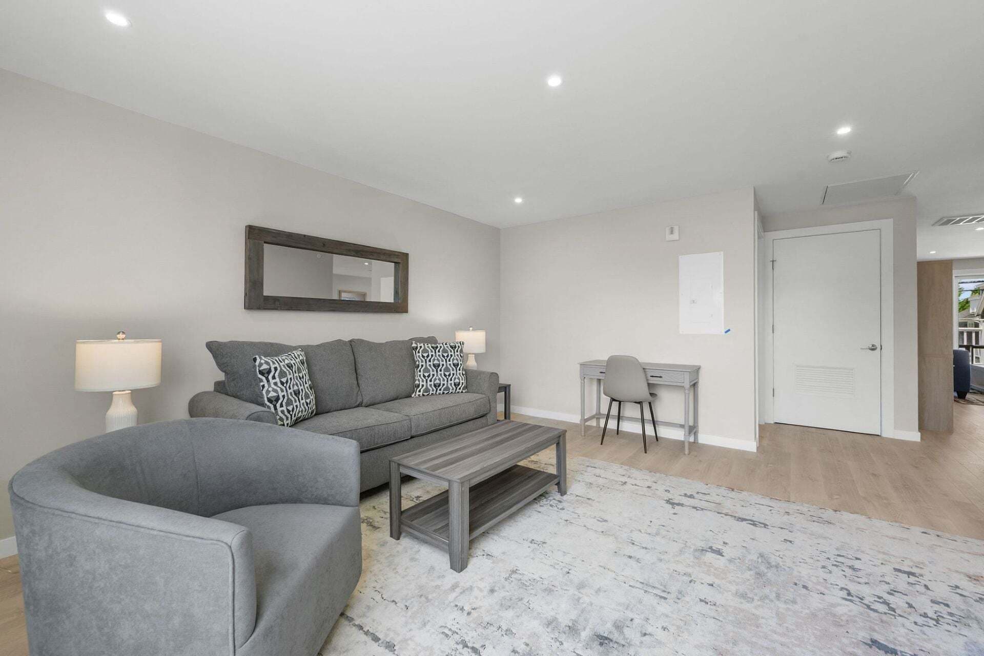 Un salon moderne avec un canapé gris, une table basse et un bureau avec une chaise.