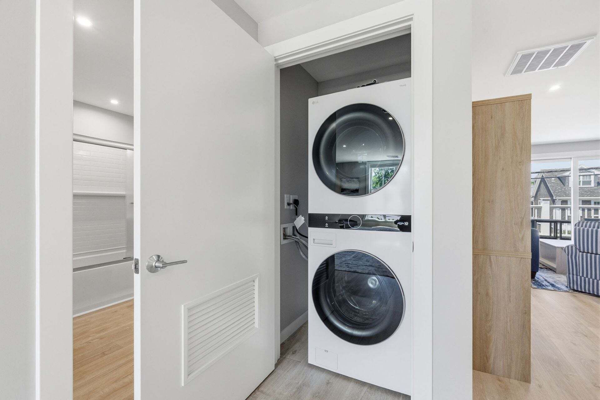 A laundry room with two front-loading washing machines, a door with a handle, and a view of the outside through a window.