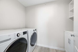 Ein Waschraum mit zwei Waschmaschinen, einem kleinen Schrank und einer weißen Wand.