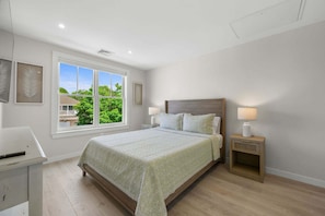 A bedroom with a large window, a bed, bedside tables, and a desk. - Beachside Harwich Port Apartment Near Town (Harwich Port)