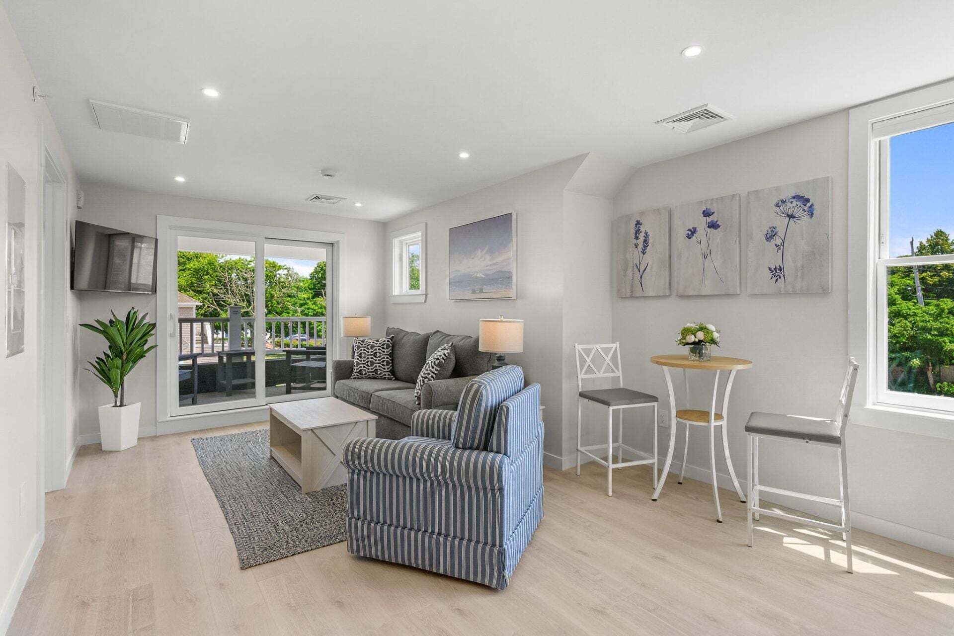 A modern living room with a sofa, armchair, coffee table, and a dining area with a chair and table.